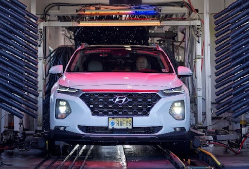 a man sits in a car as it passes through an automatic car wash - Spark